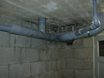 Nieuwe grijze pvc-afvoerleidingen onder een betonnen plafond